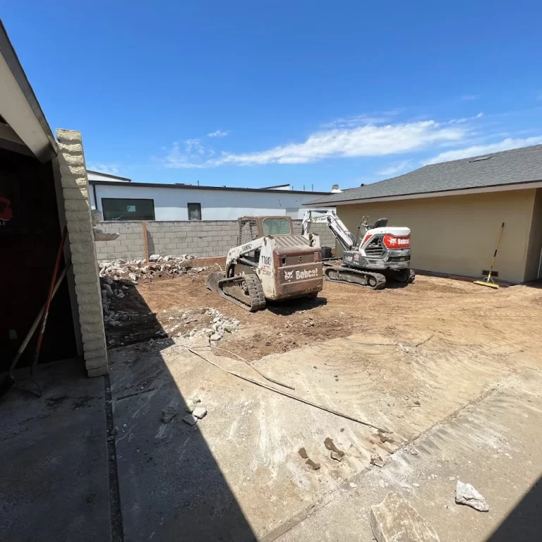 Pool demolition and removal in progress on an Orange County residential property, showing the pool shell being broken up and backfilled